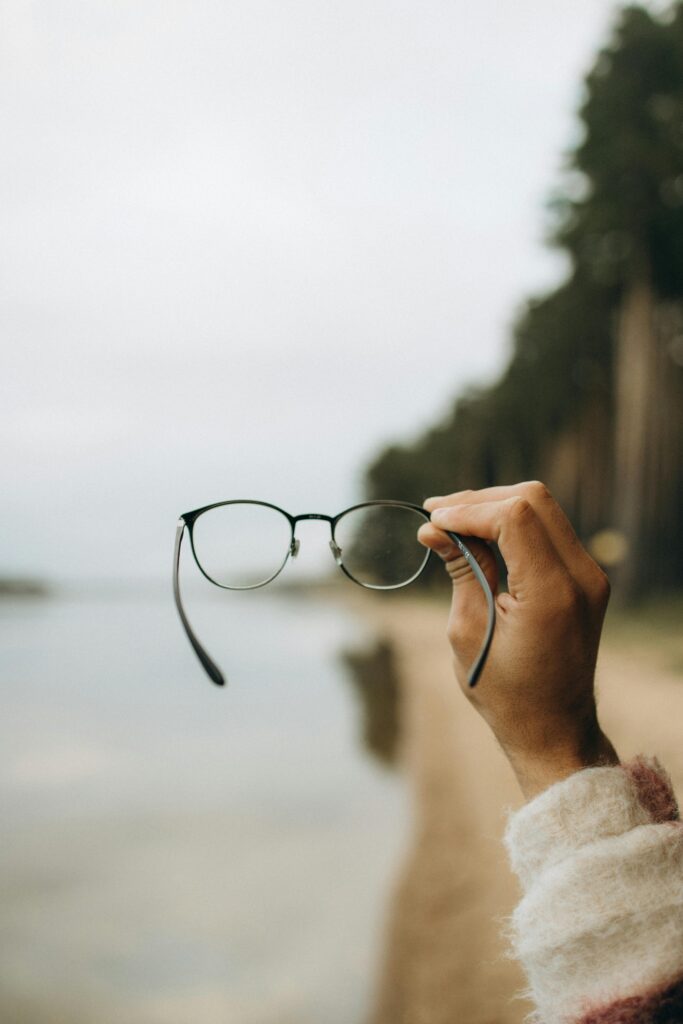 Selective Focus Photo of a Persons Hand Holding Black Framed Eyeglasses - Vision Source Mandan