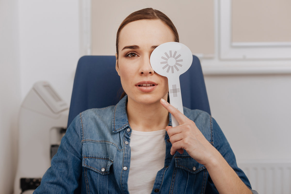 Visit to the oculist. Nice pleasant young woman closing her left eye and looking in front of her while visiting the oculist