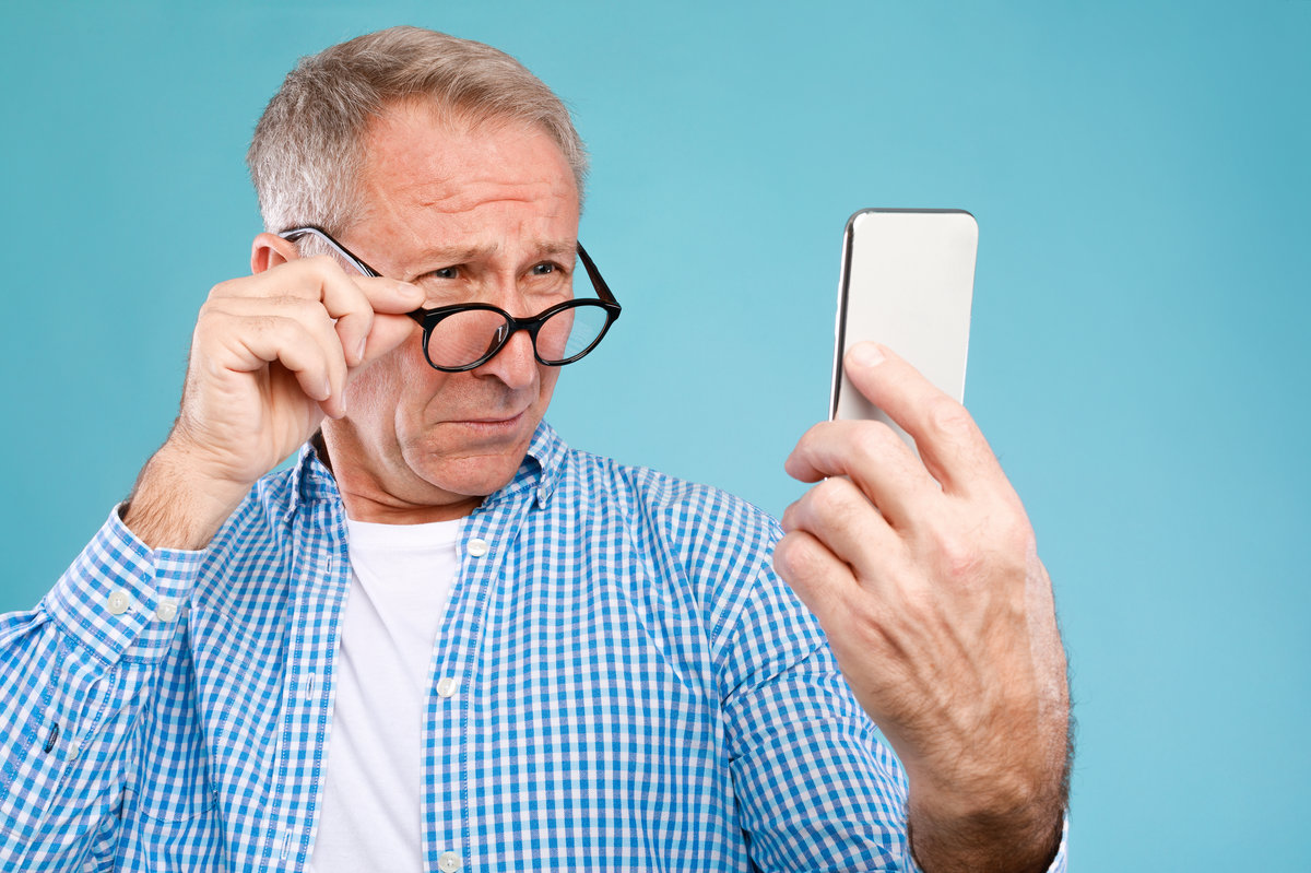 Poor Eyesight. Senior Man Squinting Eyes Reading Message On Phone Wearing Eyeglasses Having Problems With Vision, Blue Studio. Ophtalmic Issue, Bad Sight In Older Age, Macular Degeneration Concept