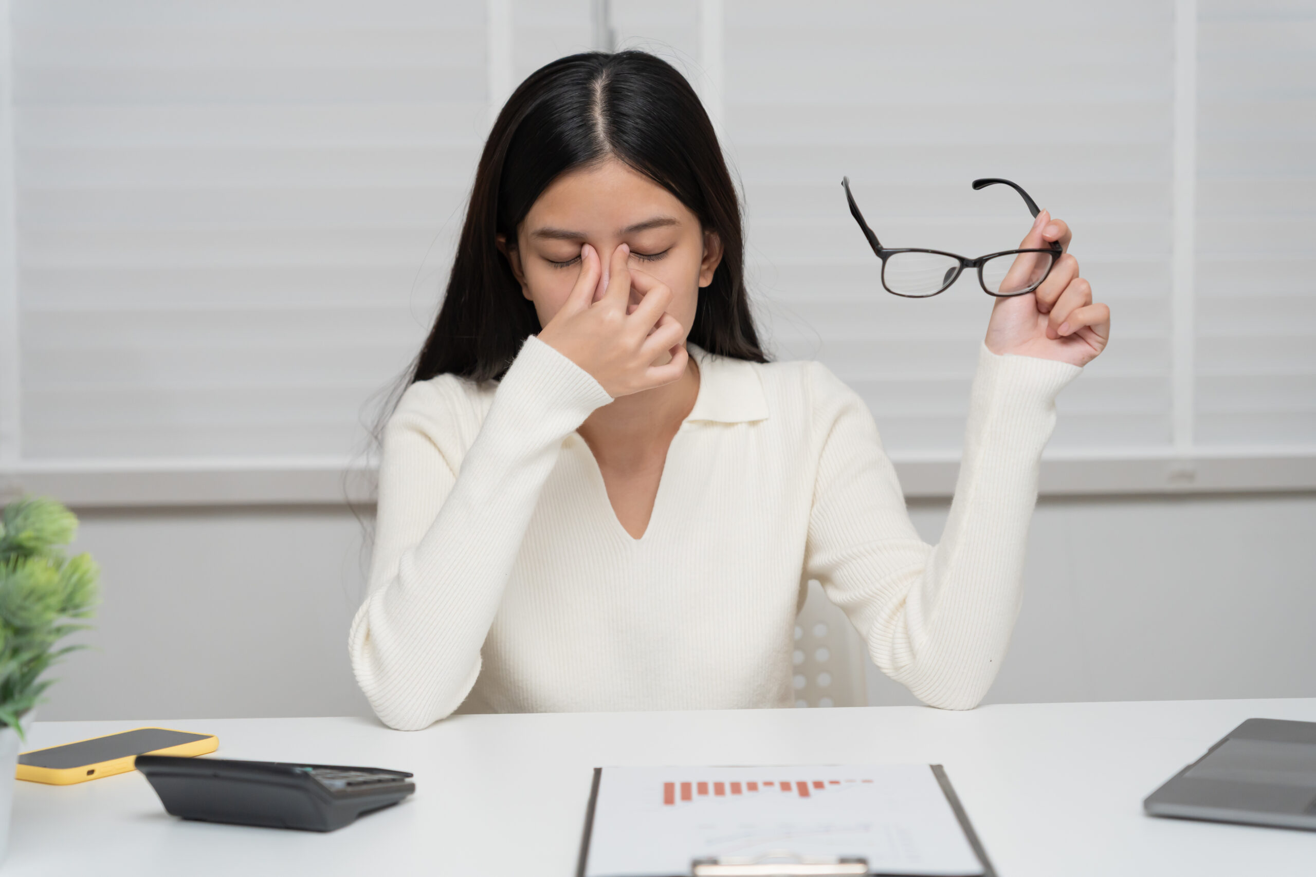 Eye problems, Asian women with tired and irritated eyes, eye rubbing, dry, eye pain after work, migraine, headache, blurred vision, photophobia, working in the dark, blue light from computer screens