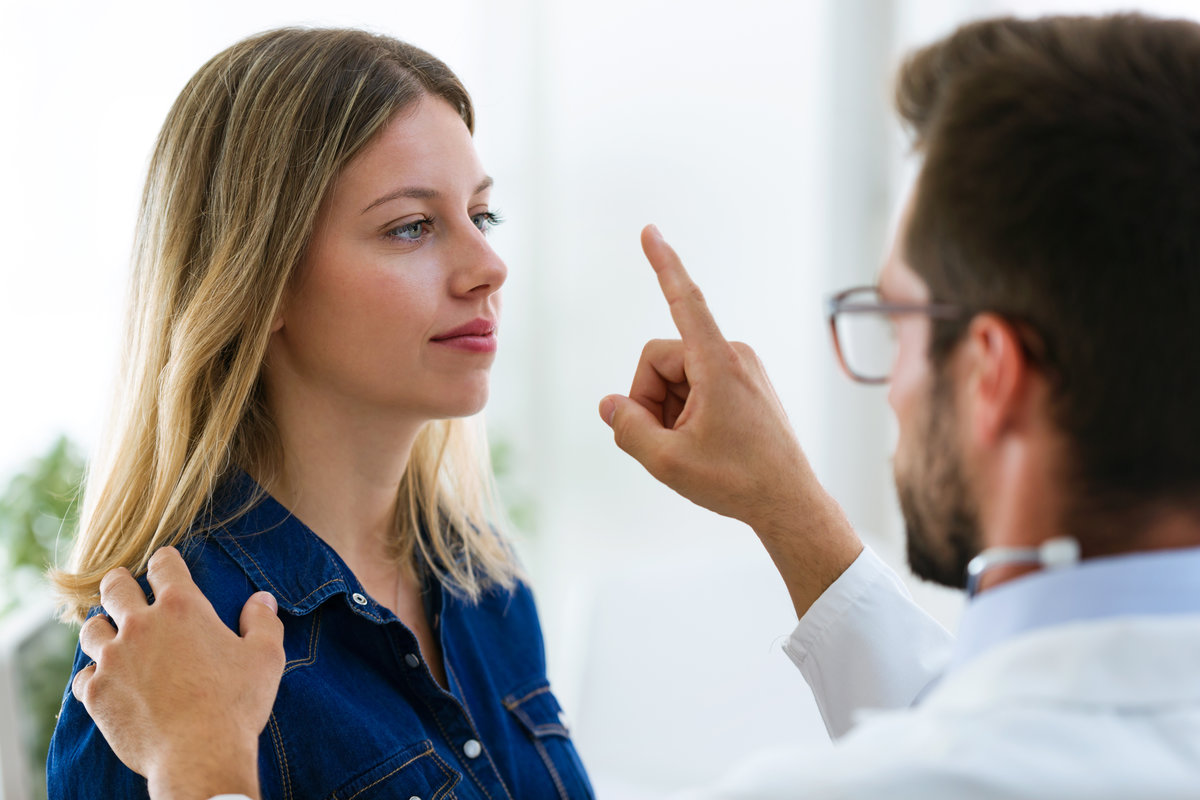 Shot of attractive male doctor ophtalmologist checking the eye vision of beautiful young woman in modern clinic.