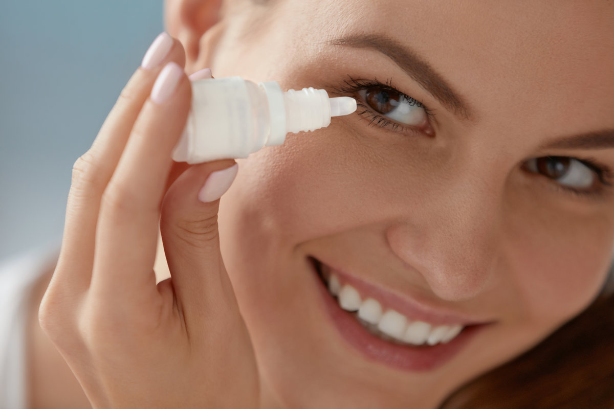 Eye drop. Woman applying lubricant eye drops in her eyes closeup. Happy smiling girl with artificial tears bottle