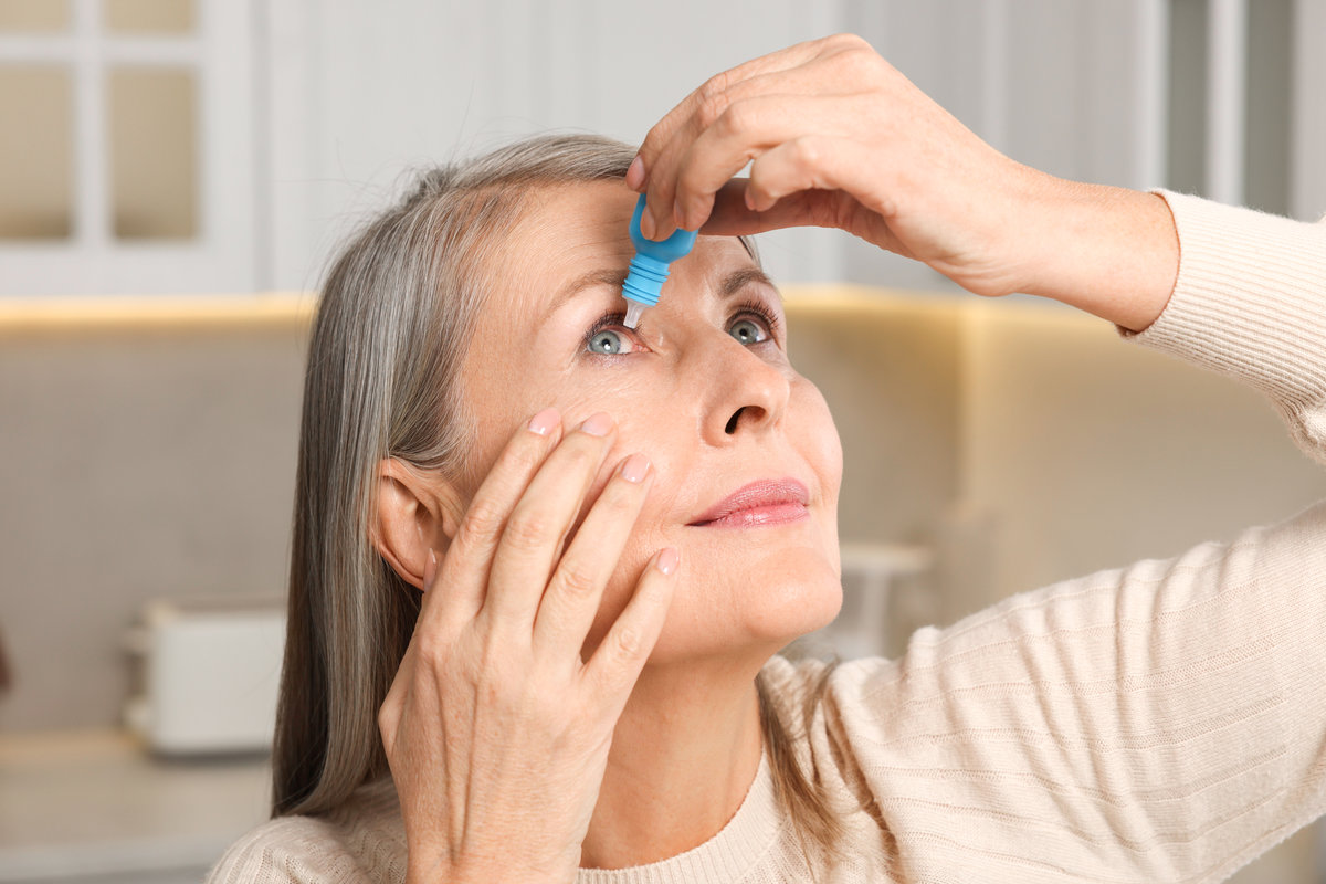 Woman applying medical eye drops at home