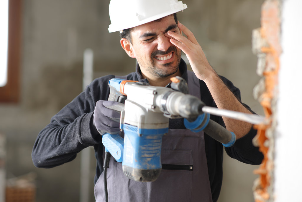 Construction worker suffering accident in an eye working with a rotary hammer without protection glasses