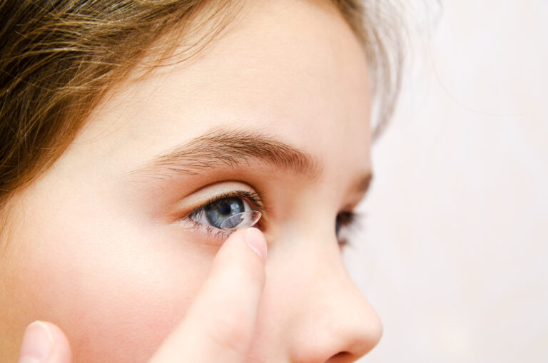 Little girl child putting contact lens into her eye closeup vision concept