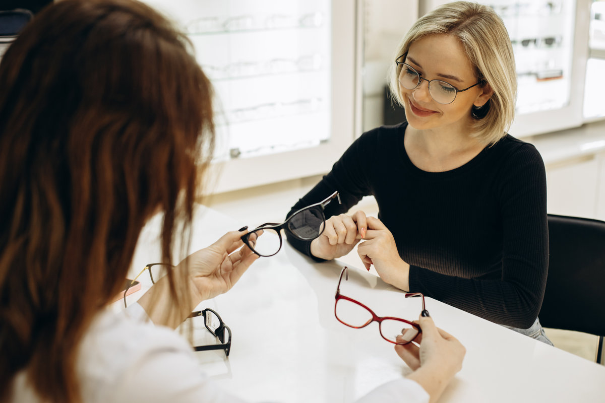 Woman choosing a pair of eyeglasses at optics store