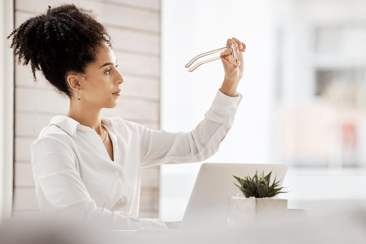 Business, black woman and glasses for reading on laptop in a clean office with vision, focus and eye care. Female entrepreneur at desk with fashion eyeglasses while thinking of innovation strategy.