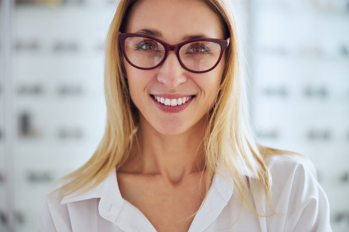 Close up portrait of pretty lady in white shirt and eyeglasses looking and posing at the photo camera in medical center