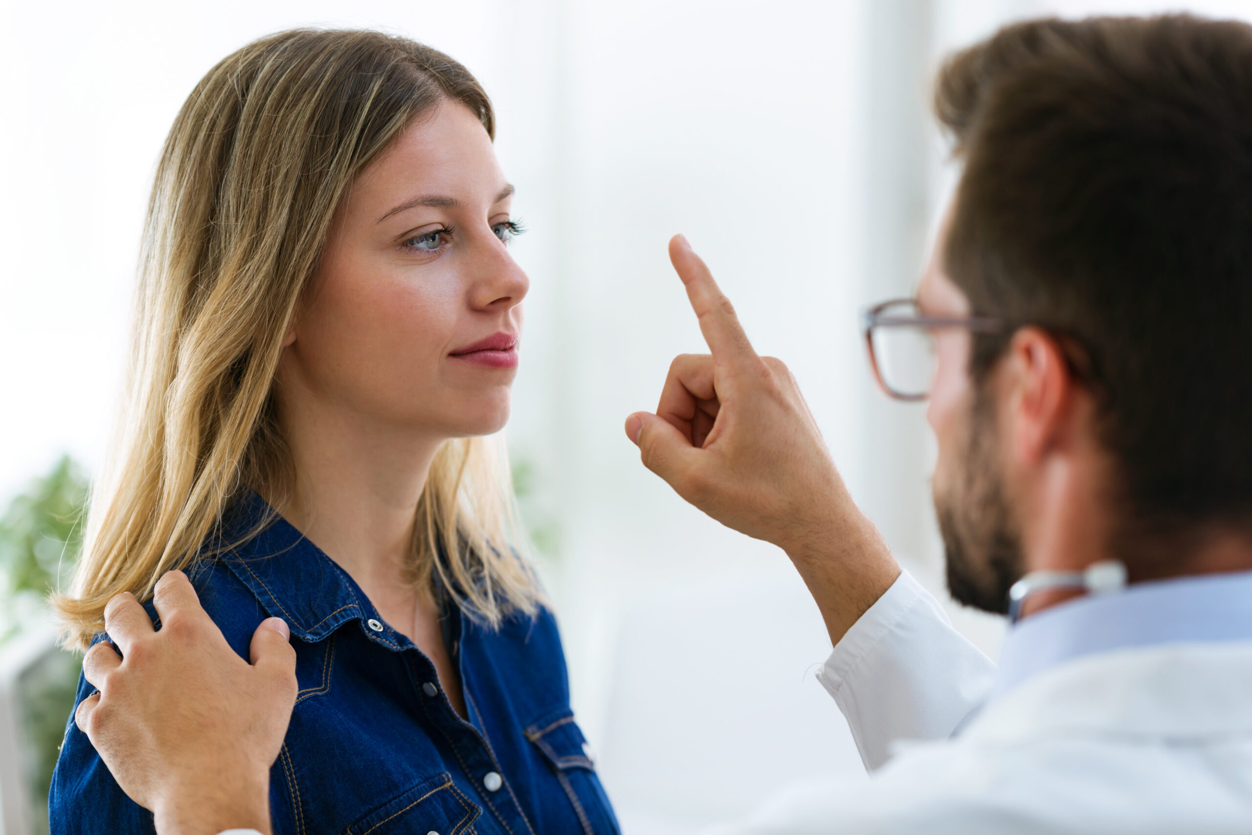 Shot of attractive male doctor ophtalmologist checking the eye vision of beautiful young woman in modern clinic.