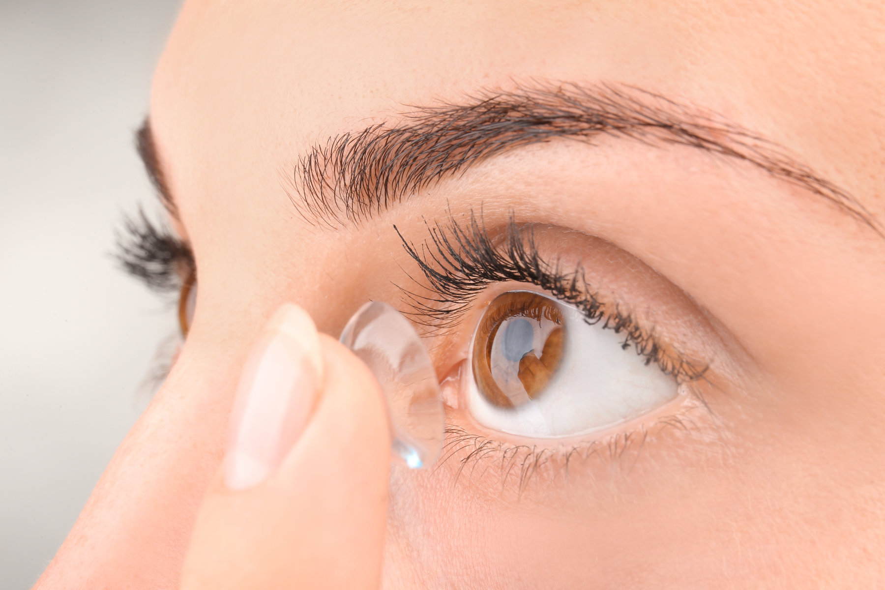 Young woman putting contact lens, closeup