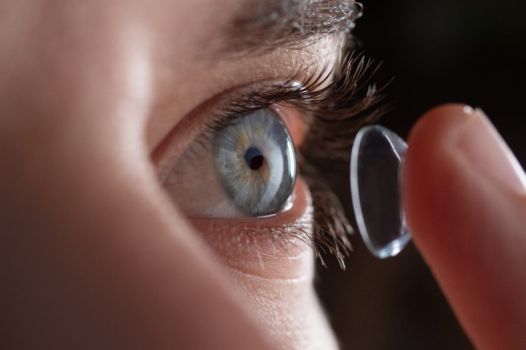 Close-up of a man putting contact lenses on blue eye. Concept of