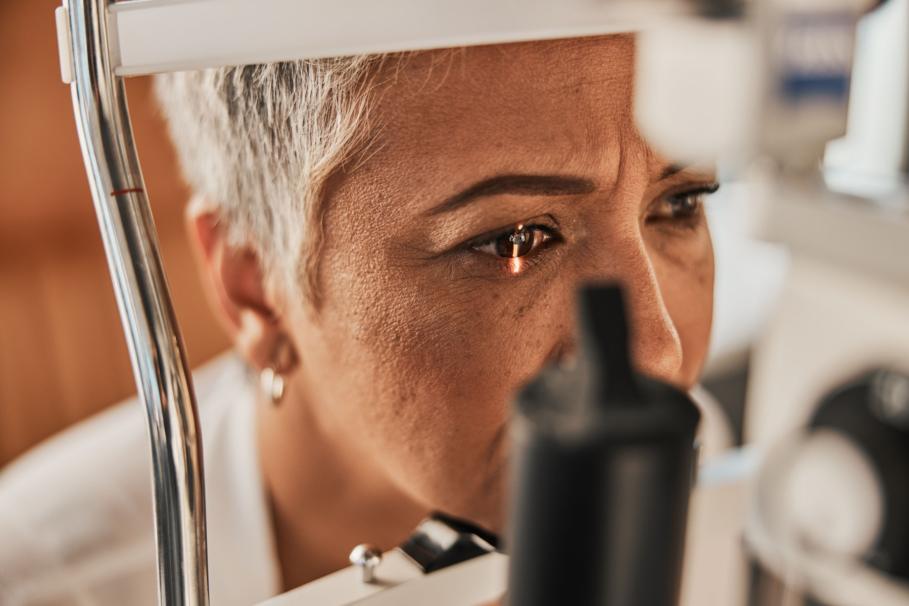 Laser, vision or senior customer in eye exam for eyesight at optometrist office in assessment or consultation. Face of mature woman testing or checking vision to help iris or retina visual health.